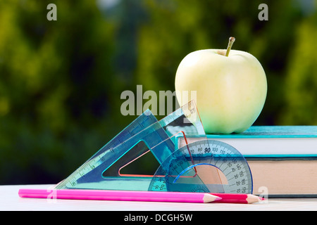Tools for school with apple placed near on green background Stock Photo