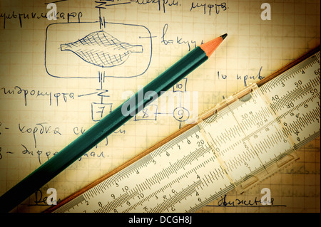 pencil and a slide rule on the old page with the calculations in mechanics Stock Photo