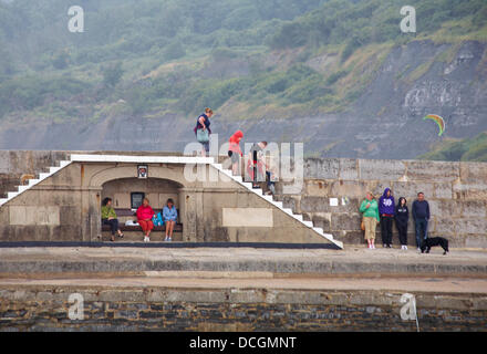 Lyme Regis, UK 17 August 2013. Tourists brave the wet weather. Visitors try and find shelter by the Cobb Cob harbour wall. Credit:  Carolyn Jenkins/Alamy Live News Stock Photo