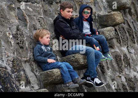 Lyme Regis, UK 17 August 2013. Tourists brave the wet weather. Three boys sitting on stone steps of the Cobb Cob harbour wall. Credit:  Carolyn Jenkins/Alamy Live News Stock Photo