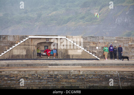 Lyme Regis, UK 17 August 2013. Tourists brave the wet weather. Visitors try and find shelter by the Cobb Cob harbour wall. Credit:  Carolyn Jenkins/Alamy Live News Stock Photo