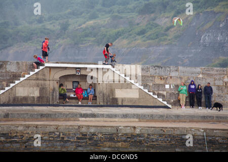 Lyme Regis, UK 17 August 2013. Tourists brave the wet weather. Visitors try and find shelter by the Cobb Cob harbour wall. Credit:  Carolyn Jenkins/Alamy Live News Stock Photo