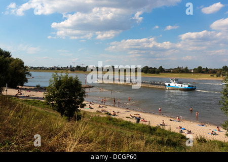 Freight ship on the Rhine with people on the beach and in the water swimming, at Düsseldorf Stock Photo