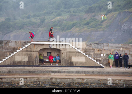 Lyme Regis, UK 17 August 2013. Tourists brave the wet weather. Visitors try and find shelter by the Cobb Cob harbour wall. Credit:  Carolyn Jenkins/Alamy Live News Stock Photo