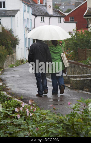 Lyme Regis, UK 17 August 2013. Tourists brave the wet weather. Couple walk along path under umbrella trying to keep dry under the shelter. Credit:  Carolyn Jenkins/Alamy Live News Stock Photo