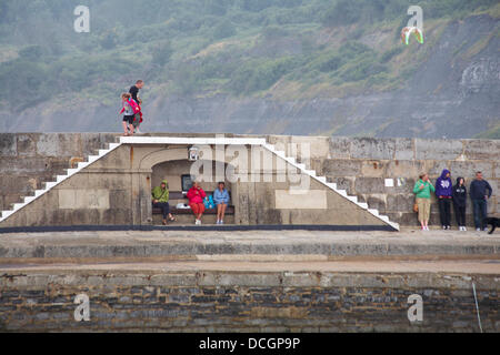 Lyme Regis, UK 17 August 2013. Tourists brave the wet weather. Visitors try and find shelter by the Cobb Cob harbour wall. Credit:  Carolyn Jenkins/Alamy Live News Stock Photo