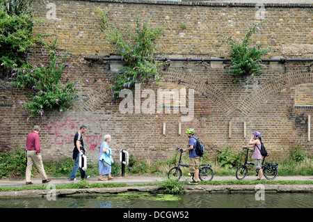 Leisure cyclists giving way to pedestrians or walkers on the Regent's Canal towpath, London Borough of Camden, England, UK Stock Photo