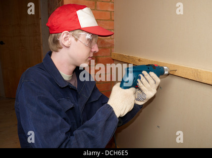 The worker drills wooden board Stock Photo