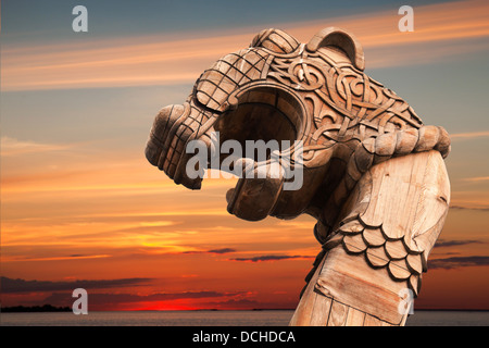 Carved wooden dragon on the bow of Viking ship above evening cloudy sky Stock Photo
