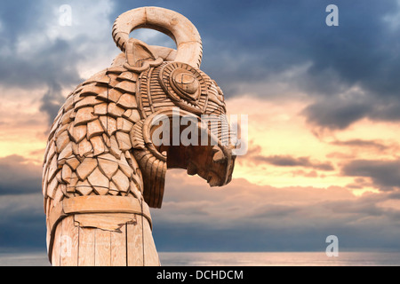 Carved wooden dragon on the bow of Viking ship above morning sky and sea Stock Photo