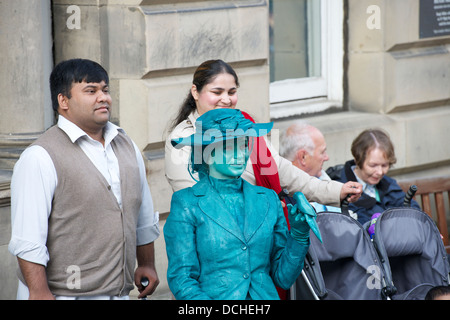 Busker posing with a couple on the High Street, Edinburgh during the Festival Fringe. Stock Photo