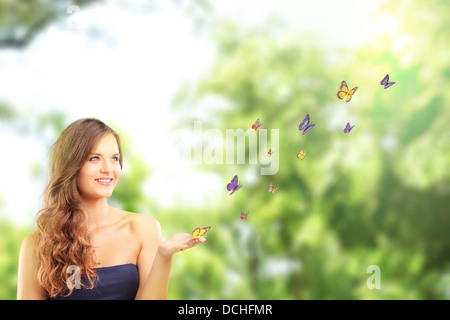 Beautiful female with a butterfly on her hand, in a park Stock Photo