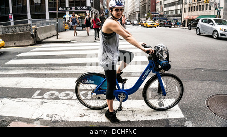 smiling young woman on bicycle from Citibike bike sharing system rides in bicycle lane at Park Avenue South & 34th Street Stock Photo