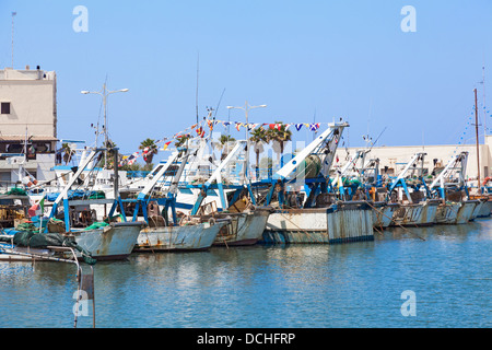 Italian fishing boats moored in the harbour at Mola di Bari in Apulia, southern Italy under a bright blue sky Stock Photo