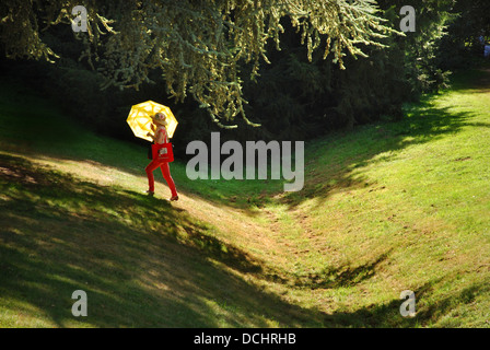 woman in red walking uphill at Dyck castle gardens Germany Stock Photo