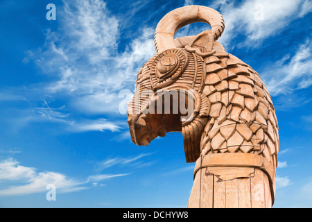 Carved wooden dragon on forepart of the ancient Viking ship above dramatic blue sky Stock Photo