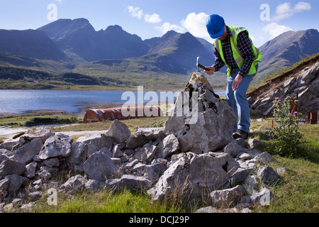 Rock outcrop and Bla Bheinn and Beinn Na Caillich Cuillin mountains; Geologist at Loch Slapin Marble quarry at Ben Suardal, Isle of Skye, Scotland, UK Stock Photo