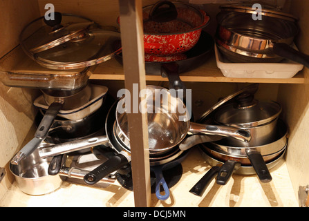 Saucepans in a jumbled kitchen cupbaord. Stock Photo