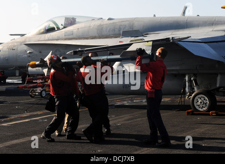 Sailors assigned to the Golden Warriors of Strike Fighter Squadron (VFA) 87 attach ordnance to an F/A-18A Hornet on the flight deck of the aircraft carrier USS George H.W. Bush (CVN 77). George H.W. Bush is conducting tailored ship's training availability Stock Photo