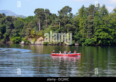 Group of young people in a large rowing boat enjoying a day on Lake Windermere in the Lake District National Park Stock Photo