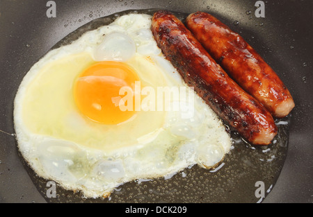 Closeup of sausages and an egg frying in a pan Stock Photo