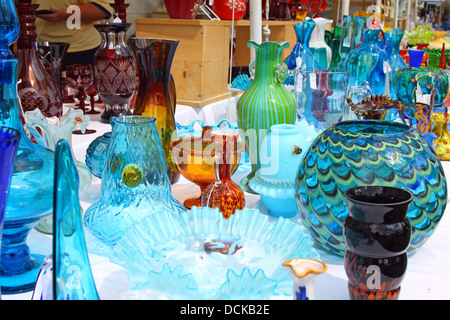 Collection of colorful vintage glassware is displayed on a sale table at an Antique Flea Market Stock Photo