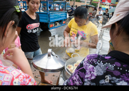 People are buying steamed pork buns (bao) from a vendor on a city street in Siem Reap, Cambodia. Stock Photo
