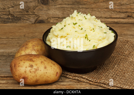 Creamy mashed potatoes in a black bowl in a rustic farmhouse setting Stock Photo