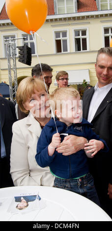 Greifswad, Germany. 20th Aug, 2013. German Chancellor and chairperson of the CDU, Angela Merkel (L) holds a child on her arm after a campaign rally in Greifswad, Germany, 20 August 2013. Greifswald will belong to Merkel's constituency for the first time in the general elections 2013. Photo: STEFAN SAUER/dpa/Alamy Live News Stock Photo