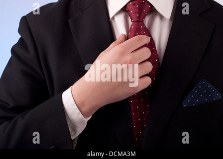 Young adult man in black suit and burgundy tie Stock Photo