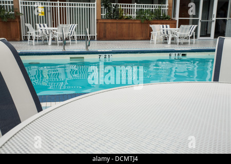 Hotel pool has chairs and tables for guests. Stock Photo