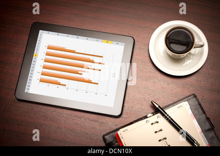 Modern workplace with digital tablet showing charts and diagram on screen Stock Photo