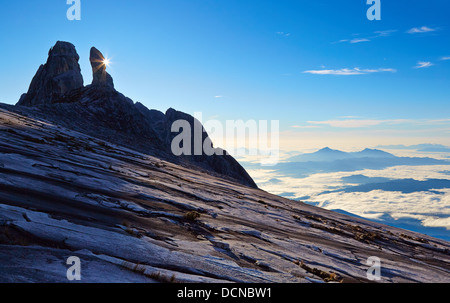 Starburst sunrise behind Donkey's Ears peak on Mount Kinabalu in Sabah Borneo with a view of cloud wreathed mountains