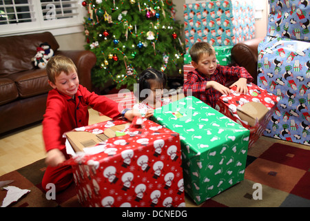 Three children opening gifts on Christmas day Stock Photo  Alamy