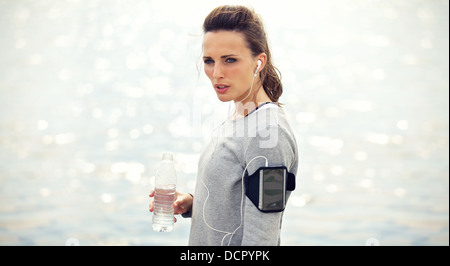 Female runner with bottled water tired from running Stock Photo