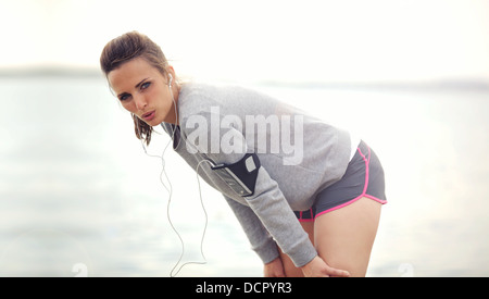 Tired female athlete outdoors resting after running Stock Photo