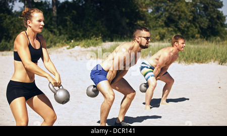 Group doing crossfit workout on beach on a hot summer day Stock Photo