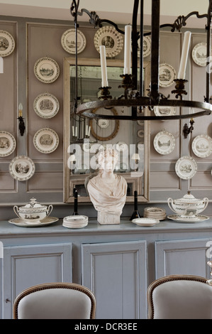 Wood wall paneling with decorative china plates in dining room with stone bust Stock Photo
