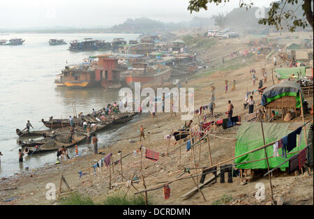 Different types of vessels and boats are unloaded by muscular strength at the bank of the Ayeyarwady river near Mandalay. Stock Photo