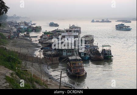 Numerous boats and vessels are moored at the bank of the Ayeyarwady river near Mandalay at twilight. Stock Photo