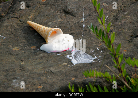 Dropped ice cream cone melting on ground Stock Photo