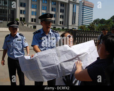 Jinan, China. 22nd Aug, 2013. A protesting woman is led away by police officers in front of the people's court in the province Shandong in Jinan, China, 22 August 2013. On Thursday the trial against top politician Bo Xilai starts who is accused of 'corruption, embezzlement, and abuse of office'. Photo: STEPHAN SCHEUER/dpa/Alamy Live News Stock Photo