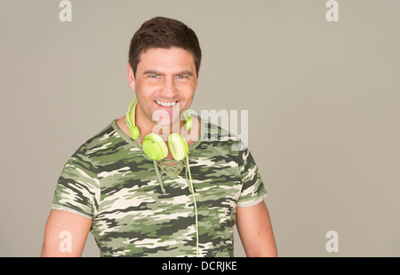 Man with camouflage t-shirt and green headphones smiling at camera Stock Photo