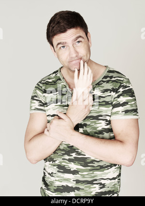 Portrait of man in camouflage shirt looking up with thoughtful expression Stock Photo