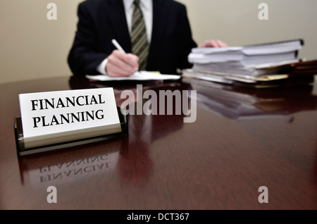 Man sitting at desk holding pen papers with business card for Financial Planning Stock Photo