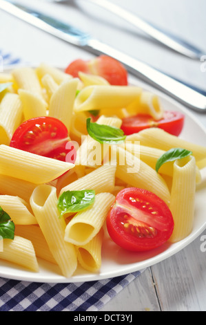 Plate of pasta with cherry tomatoes and basil leaves on table closeup ...