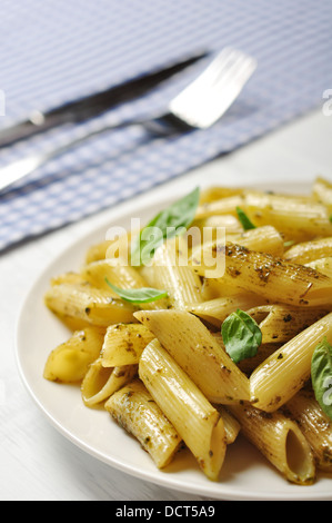 Penne pasta with pesto sauce and basil on white plate Stock Photo