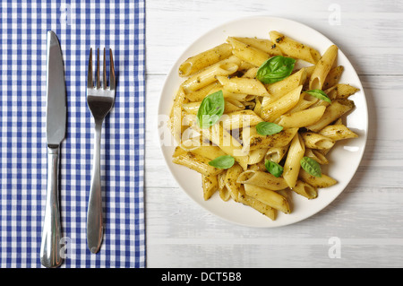 Penne pasta with pesto sauce and basil on white plate Stock Photo