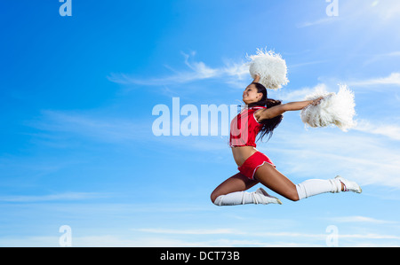 Young cheerleader in red costume jumping Stock Photo