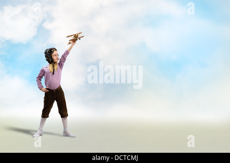 girl in helmet pilot playing with a toy airplane Stock Photo